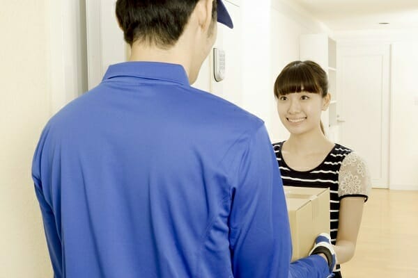 宅配買取で梱包したお酒の箱を集荷に来た配送員へ渡す様子